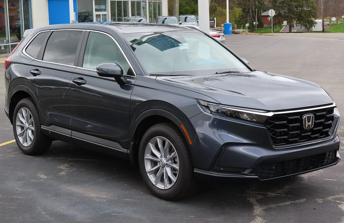 Dark gray 2023 Honda CR-V EX-L parked outside a dealership, front three-quarter view.